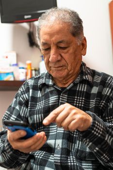 Happy senior Caucasian man looking at cellphone screen browse wireless internet. Smiling modern mature 70s grandfather text or message on smartphone. Elderly use cell technologies at home