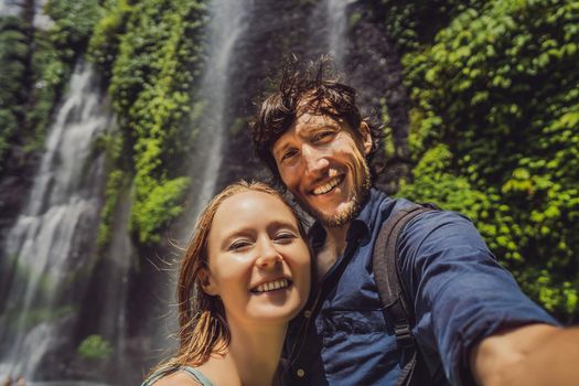 Loving couple at the Sekumpul waterfalls in jungles on Bali island, Indonesia. Bali Travel Concept.