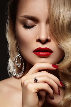 Portrait of beautiful young sexy woman with vintage make-up and blond hairstyle. Pin-up girl with red lips and manicure. American diva style with shiny brilliants jewelry