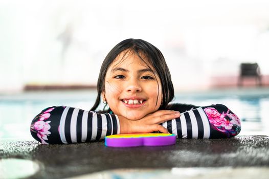 Portrait girl having fun in indoor swimming-pool. The girl is resting at the water park. Active happy kid. Swimming school for small children. Concept friendly family sport and summer vacation