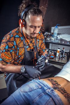 Professional tattooist makes tattoo in his salon.