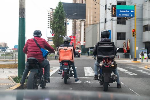 Food delivery driver with backpack on a motorcycle riding along a street