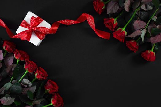 Red roses, ring and gift box on black background. Top view. Flat lay. Copy space. Still life