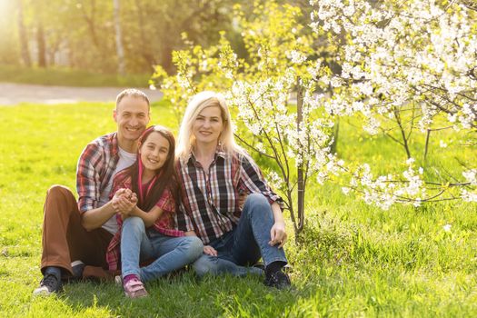 Happy family spending good time together in spring in a flowering garden.