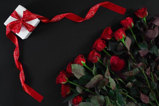 Red roses and gift box on black background. Top view. Flat lay. Copy space. Still life Valentine's Day