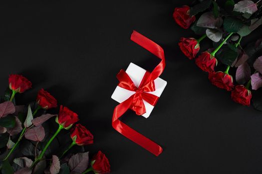 Red roses, ring and gift box on black background. Top view. Flat lay. Copy space. Still life Valentine's Day