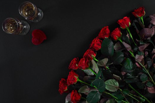 A bouquet of red roses and a box of ring on black background. View top. Flat lay. Copy space. Still life