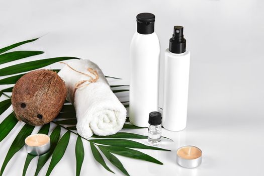 Coconut with jars of coconut oil and cosmetic cream on white background. Cosmetic lotion with green leaf and coconut. Still life. Copy space