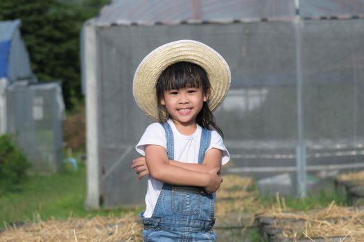 Little girl wearing a hat helps her mother in the garden, a little gardener. Cute girl playing in the vegetable garden.