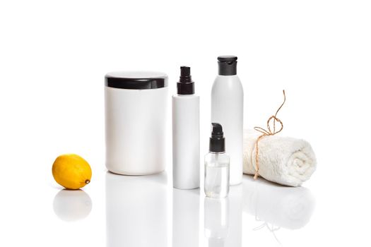 White bottles and one whole lemon isolated on white background. The concept for advertising cosmetics. Still life. Copy space