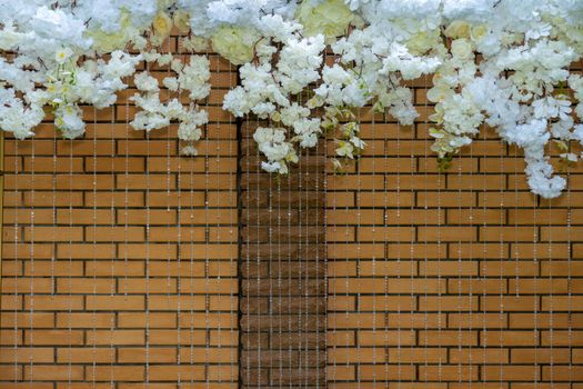 Frame of white flowers on a background of red brick fence.