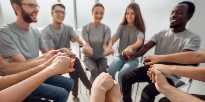 close up. a group of diverse young people holding hands