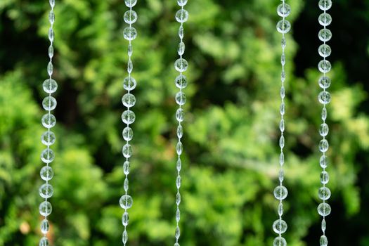 Decoration with transparent beads on a background of blurred greenery.