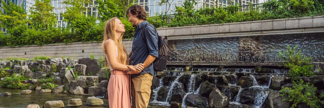 Young couple in love spends their honeymoon in Seoul. Cheonggyecheon stream in Seoul, Korea. Cheonggyecheon stream is the result of a massive urban renewal project. Travel to Korea Concept. BANNER, LONG FORMAT