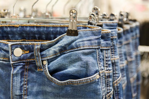 Set of blue jeans hanging on hangers in shop