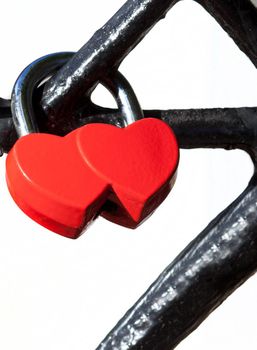 Red lock in the form of two hearts on the railing of the bridge