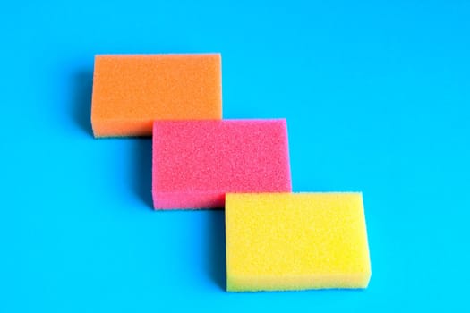 Three kitchen sponges colored on blue background