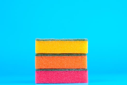 Three kitchen sponges colored on blue background