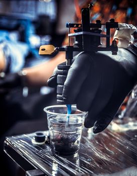 Hand of professional tattooist and a tattoo machine.