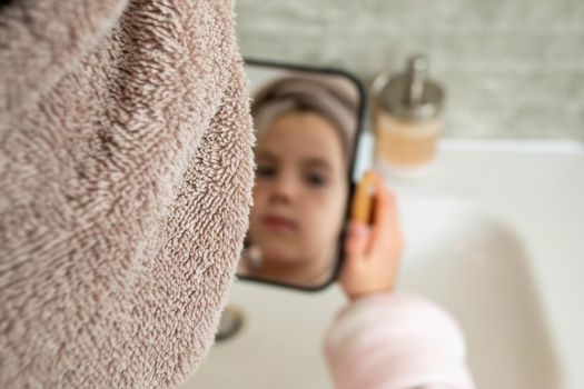 Relaxed young girl model wears towel wrapped on head, feels refreshed after taking shower, has healthy clean soft skin, poses in cozy bathroom. Girl, beauty and hygiene concept. High quality photo