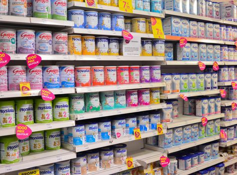 LE MANS, FRANCE - OCTOBER 12, 2017: Row of variety of artificial milk for a child on the counter of a supermarket. Powdered Baby Milk Formula