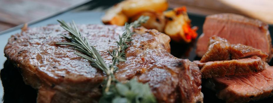 Beef steak with greens on a black plate. Steak with Basil cooked in the culinary master class. Steak banner.