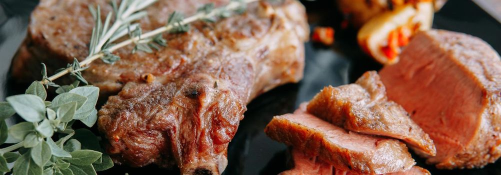 Beef steak with greens on a black plate. Steak with Basil cooked in the culinary master class. Steak banner.