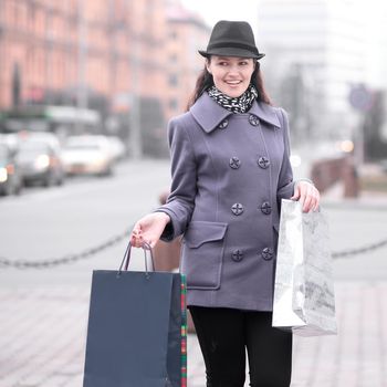 portrait of smiling woman with shopping on blurred city background.