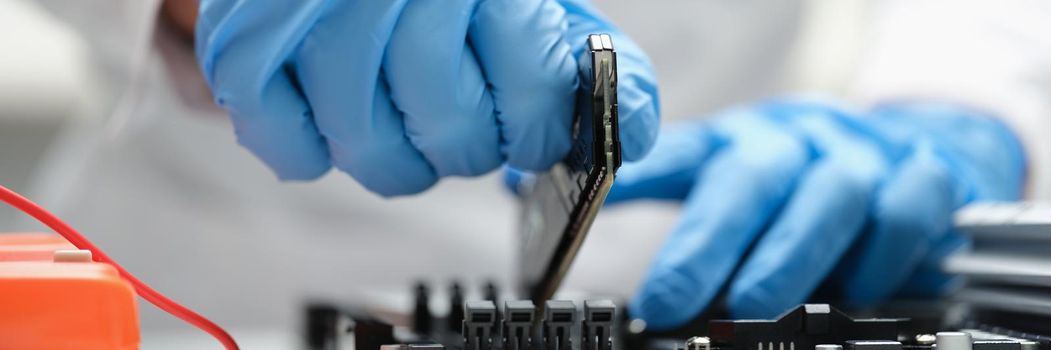 A man in production inserts a microcircuit into a device, close-up. Microchip industry, semiconductor shortage during a pandemic
