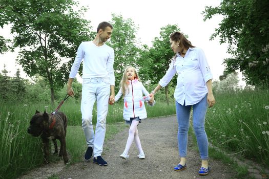 pretty daughter with her parents and pet dog in the Park in summer Sunny day.