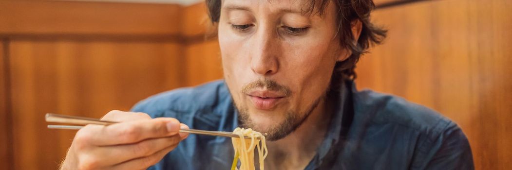 Male tourist eating Korean noodles in a Korean cafe. Travel Korea Concept. BANNER, LONG FORMAT