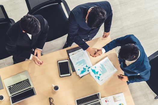 Group business people handshake at meeting table in office together with confident shot from top view . Young businessman and businesswoman workers express agreement of investment deal.