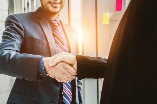 Business people handshake in corporate office showing professional agreement on a financial deal contract.