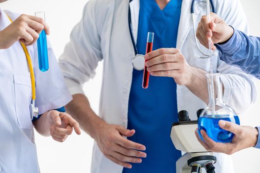 Group of scientists wearing lab coat working in laboratory while examining biochemistry sample in test tube and scientific instruments. Science technology research and development study concept.