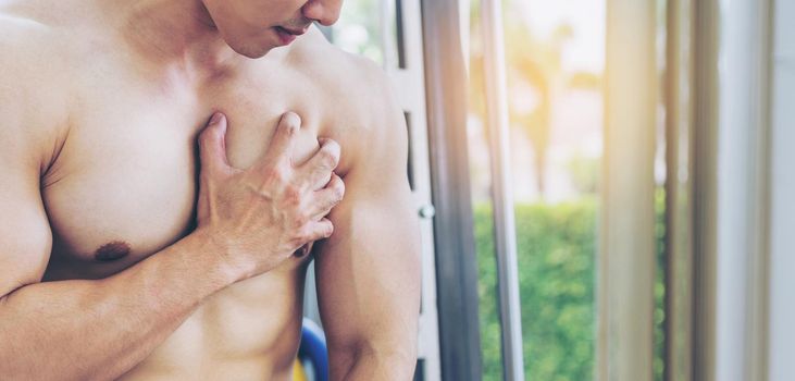 Muscular man touching his chest in fitness center. Bodybuilding concept.