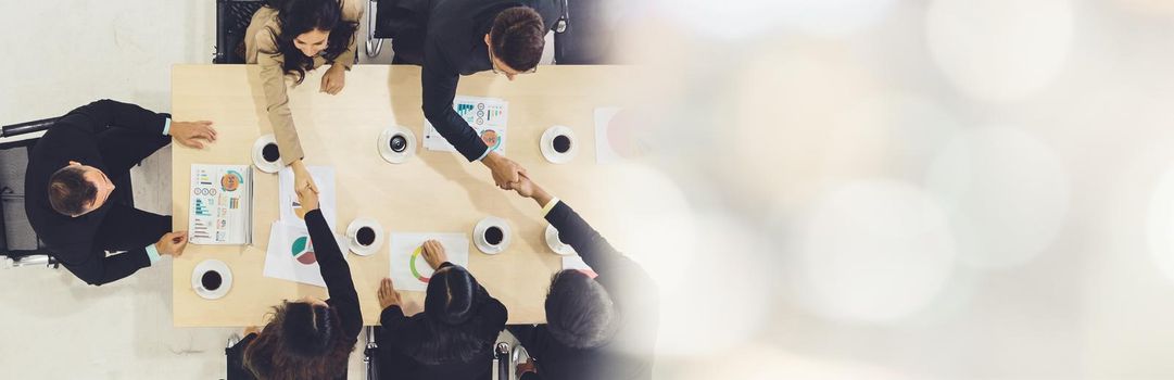 Group business people handshake at meeting table in office together with confident shot from top view . Young businessman and businesswoman workers express agreement of investment deal. broaden view