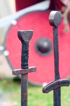 Two old swords and a shield on grass