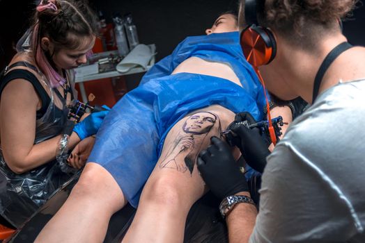 Professional tattoo artist showing process of making a tattoo in his salon.
