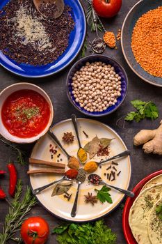 Assorted spices, herbs, chick-pea, lentil, basmati and wild rice mix, tomato chutney and pita on colorful plates. Top view. Spices and different food. Indian/ayurvedic food...