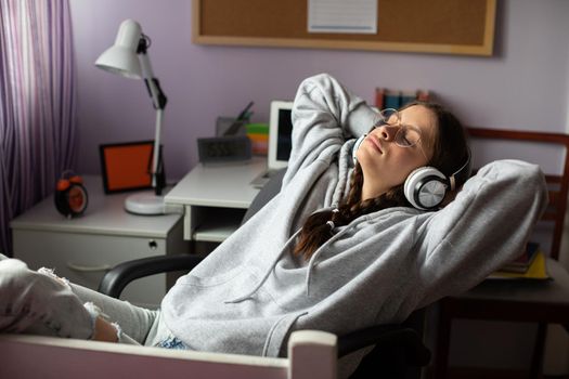 Hands above your head and eyes closed. Complete relaxation while listening to music. Young girl with pigtails and glasses is listening to music.
