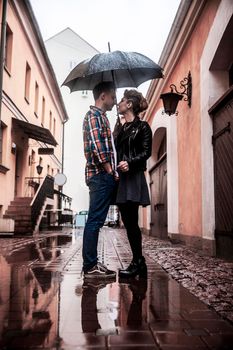 happy loving couple standing under an umbrella on a city street on a rainy day