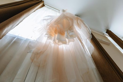 Hanging white wedding dress. Bottom view.