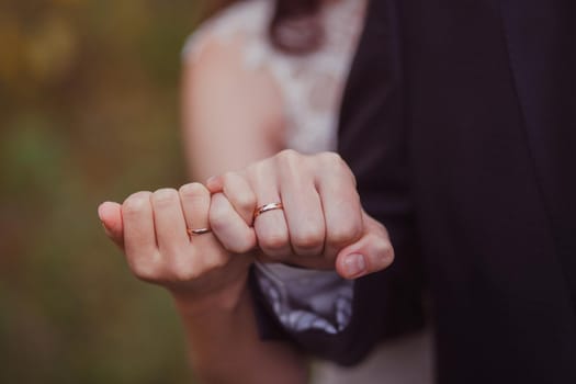 Hands of newlyweds with wedding gold rings on their fingers, close-up