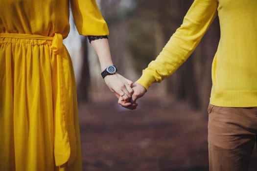 Close-up of people's hands. A man and a woman hold hands. People in yellow clothes