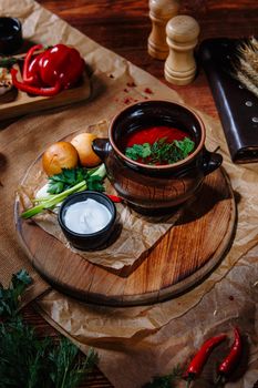 Borscht in a clay pot with sour cream and herbs. Top view