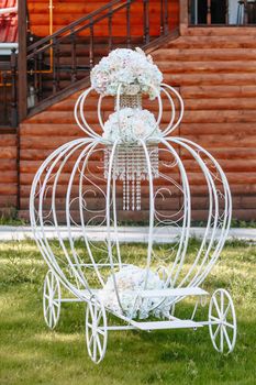 Decorative wedding carriage with flowers standing on a green lawn