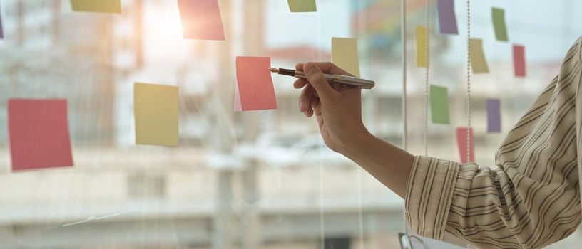 Cropped shot businessman manager writing strategy ideas on sticky notes in conference room.