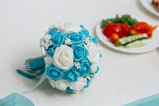 Blue wedding bouquet lying on the table. Artificial flowers