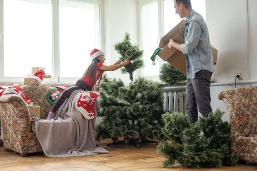 father and daughter install an artificial Christmas tree.