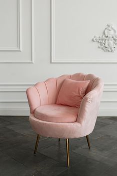 A soft pink armchair standing in a photo studio.